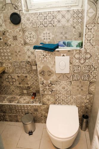 une salle de bain avec toilettes et un mur carrelé dans l'établissement Charme parisien idéal séjour à deux, à Aubervilliers