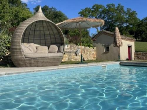 une chaise en osier avec un parasol à côté d'une piscine dans l'établissement Grande gite Saint Martin le Redon, à Soturac