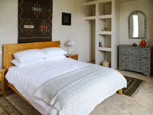 a bedroom with a large white bed and a mirror at Villa Gourza in Tassa Ouirgane