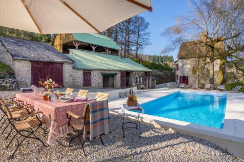 un patio avec une table et des chaises à côté d'une piscine dans l'établissement Manoir Des Chasseurs, à Saint-Prix