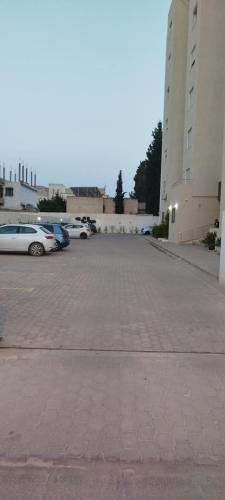 a parking lot with cars parked in front of buildings at ConfortTek apartment in Boumhel El Bassatine