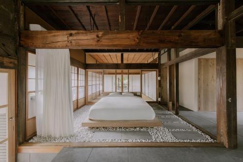 Nagara紡ノ座 築100年 一日一組限定のモダン古民家ステイ的卧室中间设有一张床