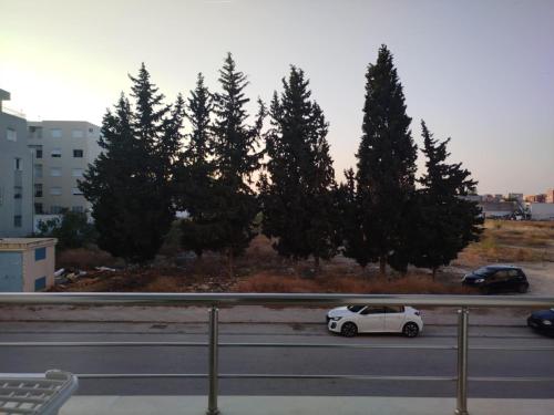 a white car parked on the side of a road at ConfortTek apartment in Boumhel El Bassatine