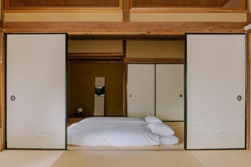 a bed in a room with two open doors at 紡ノ座 築100年 一日一組限定のモダン古民家ステイ in Nagara