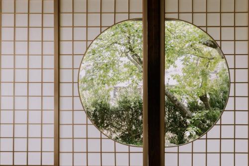 a window with a view of a tree at 紡ノ座 築100年 一日一組限定のモダン古民家ステイ in Nagara