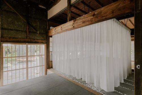 a room with a white curtain in a building at 紡ノ座 築100年 一日一組限定のモダン古民家ステイ in Nagara