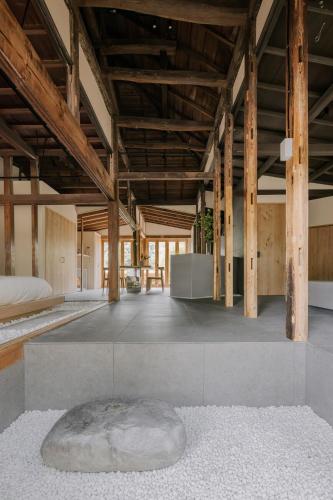 a large room with wooden ceilings and a large rock on the floor at 紡ノ座 築100年 一日一組限定のモダン古民家ステイ in Nagara