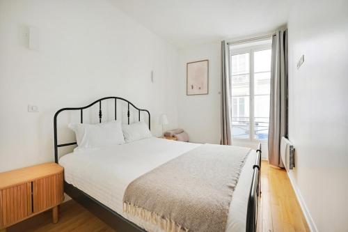 une chambre blanche avec un grand lit et une fenêtre dans l'établissement La Suite de Chatelet, à Paris