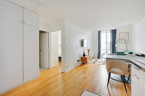 Il comprend une cuisine et une salle à manger avec des murs blancs et du parquet. dans l'établissement La Suite de Chatelet, à Paris