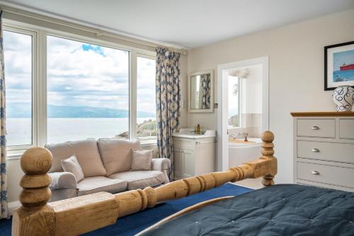 a bedroom with a bed and a couch and a window at Loch View House in Kilfinan