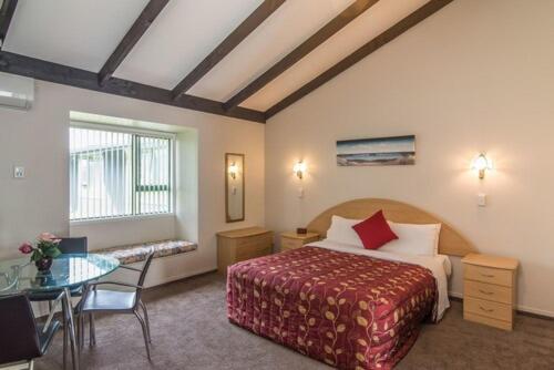 a hotel room with a bed and a table at Avana Suites in Lower Hutt