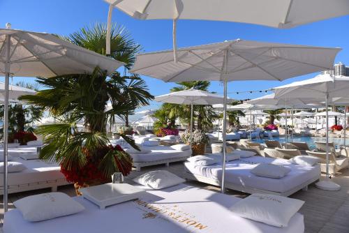 a group of white beds and umbrellas and a pool at АРКАДИЯ ОДЕССА Новые апартаменты ЖК Родос Black Sea in Odesa