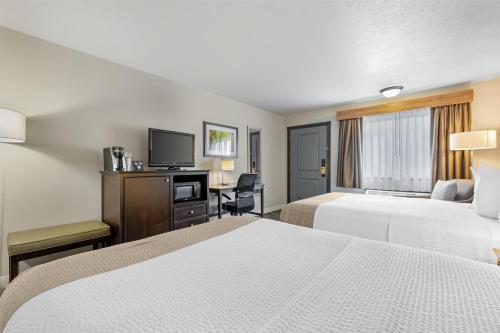 a hotel room with two beds and a flat screen tv at Best Western Black Hills Lodge in Spearfish