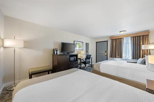 a hotel room with two beds and a flat screen tv at Best Western Black Hills Lodge in Spearfish