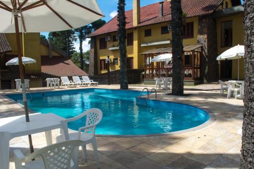 a pool with chairs and umbrellas next to a building at Estalagem Vila Suzana - Quadra de Beach Tennis Indoor in Canela