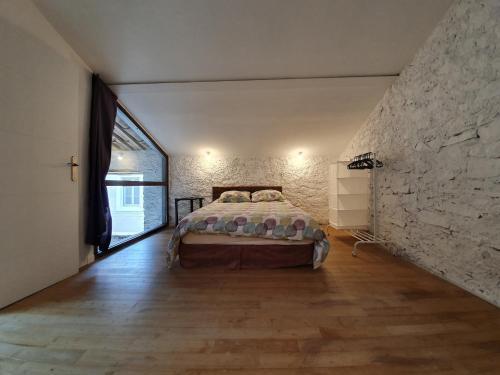 - une chambre avec un lit et un grand mur en pierre dans l'établissement Loft in Olonzac near Canal du Midi, cleaning included, à Olonzac