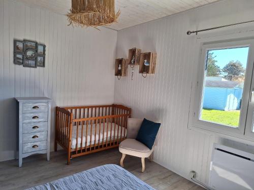 une chambre d'enfant avec un berceau, une chaise et une fenêtre dans l'établissement Holiday Home in Quiberville with Sea Views, cleaning included, à Quiberville