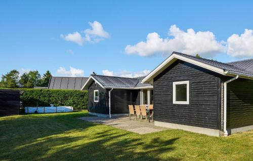 a black house with a table and chairs in a yard at 3 Bedroom Stunning Home In Fårvang in Brårup