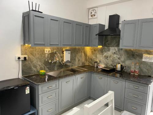 a kitchen with gray cabinets and a sink at Kasauli Hill crest By Xaria Luxury Studio Apartment in Kasauli