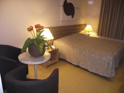 a hotel room with a bed and a table with a vase of flowers at Augustus Plaza Hotel in Sao Jose do Rio Preto