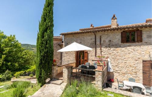 a stone house with a table and an umbrella at Lorenzo in Acqualoreto