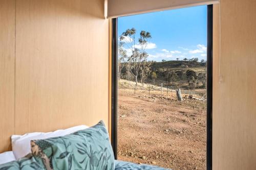 a bedroom with a window with a view of a field at Cabernet Tiny House by Tiny Away in Windeyer