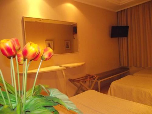 a hotel room with a vase of flowers on a table at Augustus Plaza Hotel in Sao Jose do Rio Preto