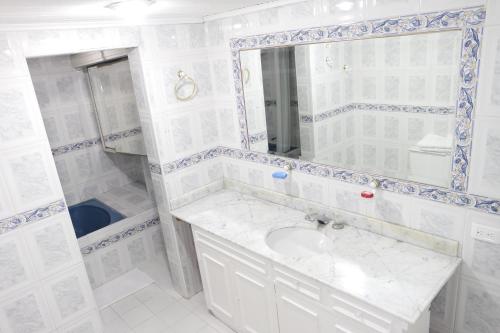 een witte badkamer met een wastafel en een spiegel bij Hotel Casa Rincón del Chicó in Bogota