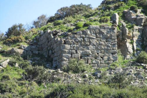 a stone wall on the side of a hill at villapetramarina in Tsakaíoi