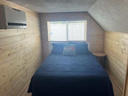 a small bedroom with a blue bed with a window at glacier creek apartment in Seward