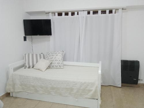 a white bed in a white room with a window at La Ñata in Tandil