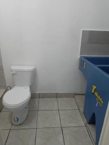 a bathroom with a toilet and a blue bin at Apartamento Retalhuleu in Retalhuleu