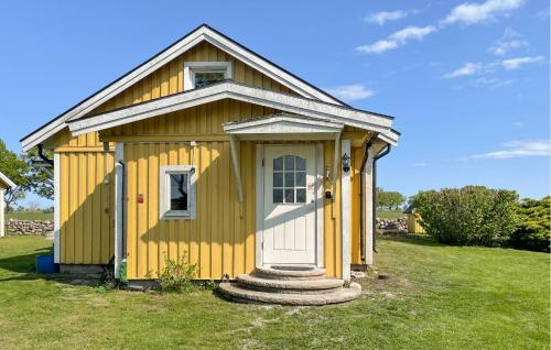 a yellow shed with a white door in a yard at Holiday Home N, Honungstorp Löttorp in Löttorp