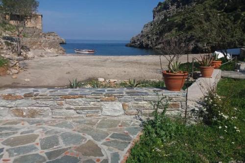 a stone walkway next to a beach with potted plants at villapetramarina in Tsakaíoi