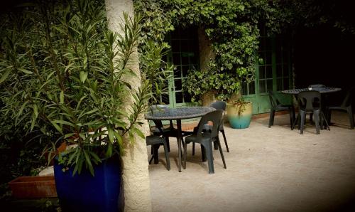 a table and chairs in a patio with plants at Les jardins du Patriarche Hôtel in Agde