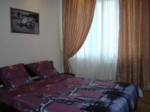 a bedroom with a bed and a window with curtains at Pleasure Apartment near center of Odessa in Odesa