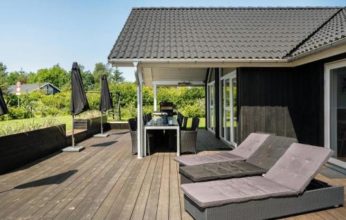 une terrasse avec une table, des chaises et un parasol dans l'établissement Stunning Home In Hadsund With Sauna, à Hadsund