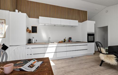 a kitchen with white cabinets and a wooden table at Gorgeous Home In Karrebæksminde in Karrebæksminde