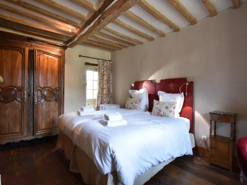une chambre avec un grand lit avec une tête de lit rouge dans l'établissement Manor in Normandy with Spa and Pool, cleaning included, à Lantheuil