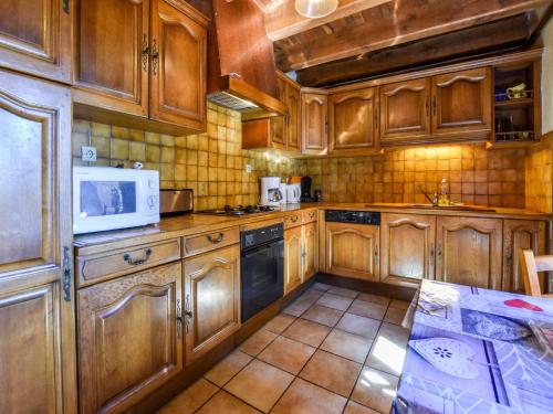 - une cuisine avec des placards en bois et un four micro-ondes dans l'établissement Holiday Home in Oradour with Terrace, cleaning included, à Neuvéglise