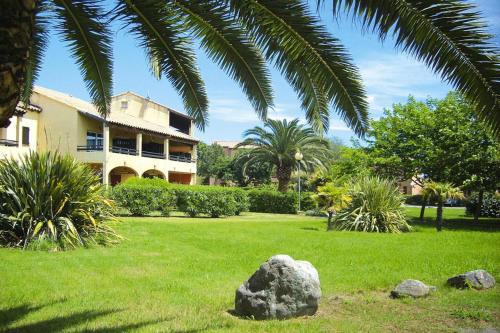 Un rocher dans l'herbe devant un bâtiment dans l'établissement Apartment in Ghisonaccia near Sandy Beach, cleaning included, à Ghisonaccia