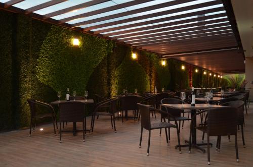 a restaurant with tables and chairs and a green wall at Loa Inn Business Centro Puebla in Puebla