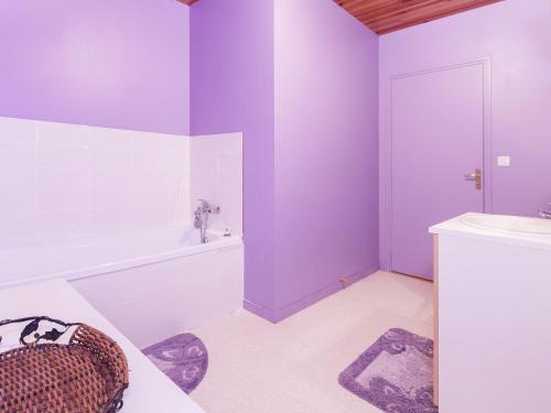 La salle de bains est pourvue de murs violets, d'une baignoire et d'un lavabo. dans l'établissement Holiday Home in Calvinet near Conques, cleaning included, à Calvinet