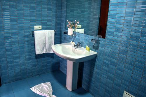 baño con lavabo y pared de azulejos azules en Hôtel Résidence Kabila Vista, en M'diq