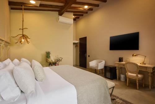 a bedroom with a white bed and a television at Tau House in Guatapé