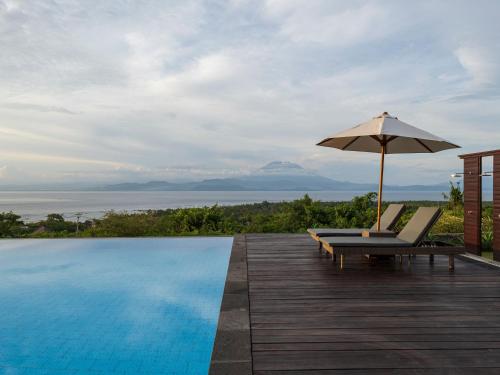 a swimming pool with an umbrella and a chair and an umbrella at Semabu Hills Hotel Nusa Penida in Nusa Penida