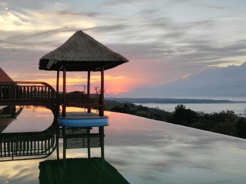 a swimming pool with a umbrella and chairs on the water at Semabu Hills Hotel Nusa Penida in Nusa Penida