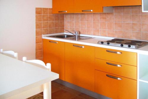 une cuisine avec des armoires orange et un évier dans l'établissement Apartment near Pinarellu Bay Beach, cleaning included, à Vardiola