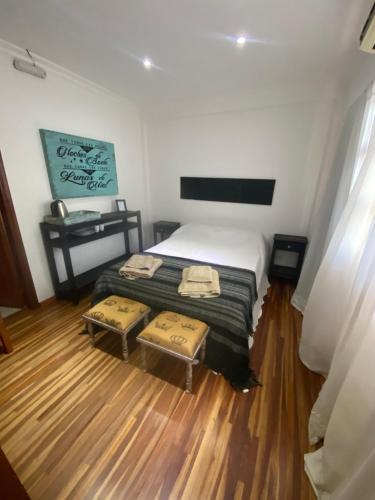 a small bedroom with a bed with two ottomans at THE HEIRS Departamentos in Posadas