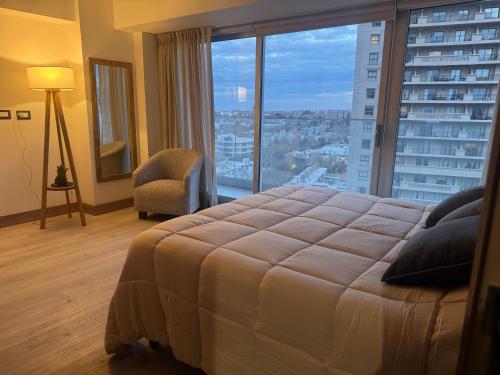 a bedroom with a large bed and a large window at Departamento espectacular con balcón panorámico en piso alto in Villa Marini